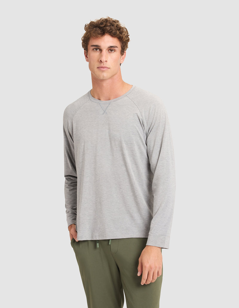 A man with curly brown hair wears the Cozy Earth Men's Bamboo Stretch-Knit Long Sleeve in light gray and olive green pants, standing against a plain light gray background.