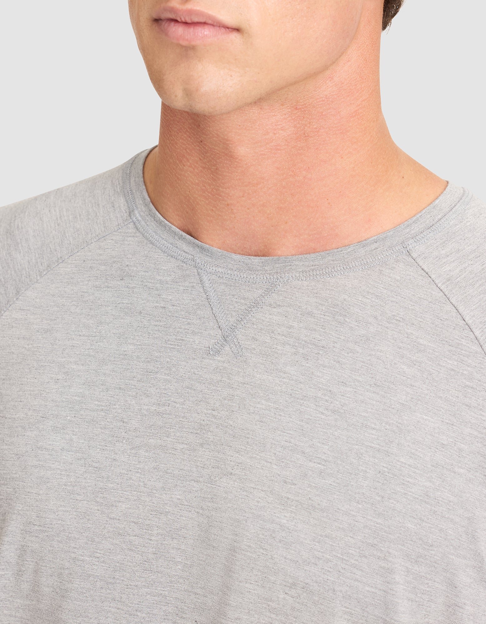 A close-up of a man wearing the Cozy Earth Men's Bamboo Stretch-Knit Long Sleeve, highlighting the crew neckline and part of his face and shoulder against a plain background. 