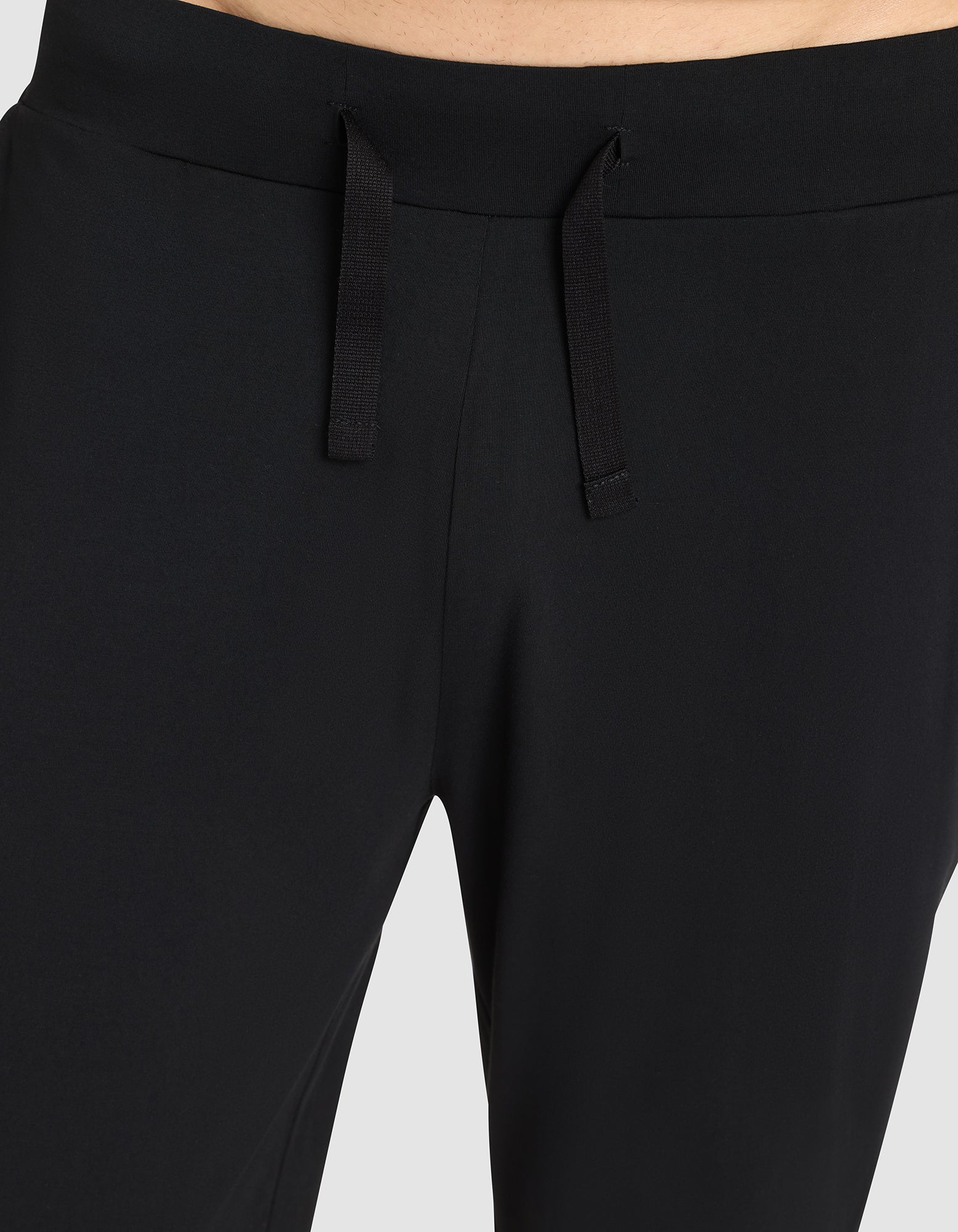 Close-up of a person wearing Cozy Earth Men's Bamboo Stretch-Knit Pajama Pant, highlighting the drawstring waist and upper section against a light background. 