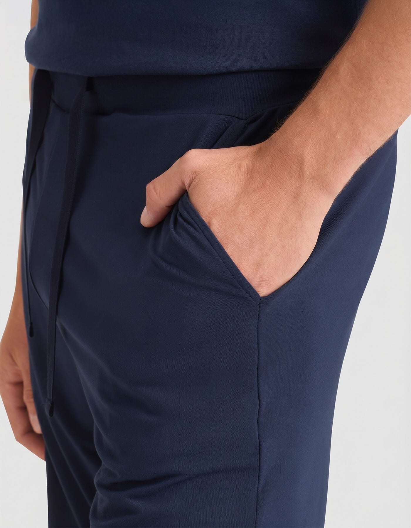 A man wearing Cozy Earth's Men's Bamboo Stretch-Knit Short Sleeve Pajama Set in navy stands with one hand in his pocket against a neutral background.