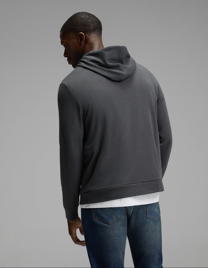 A man wearing the Cozy Earth Men’s Brushed Bamboo Hoodie in dark gray and blue jeans stands with his back to the camera against a plain gray background.