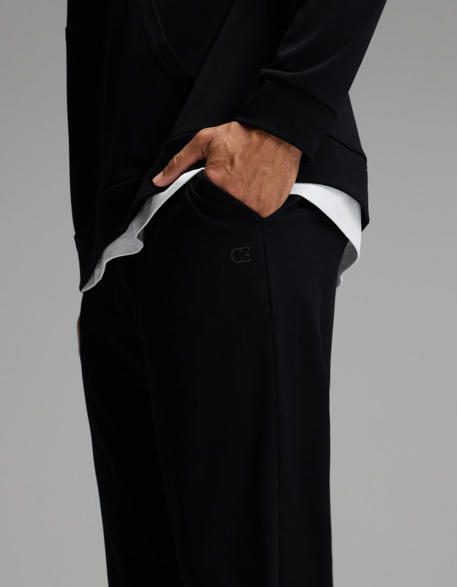 A person wearing Cozy Earth Men’s Brushed Bamboo Joggers paired with a black long-sleeve top, hand in pocket, revealing a layered white shirt underneath.