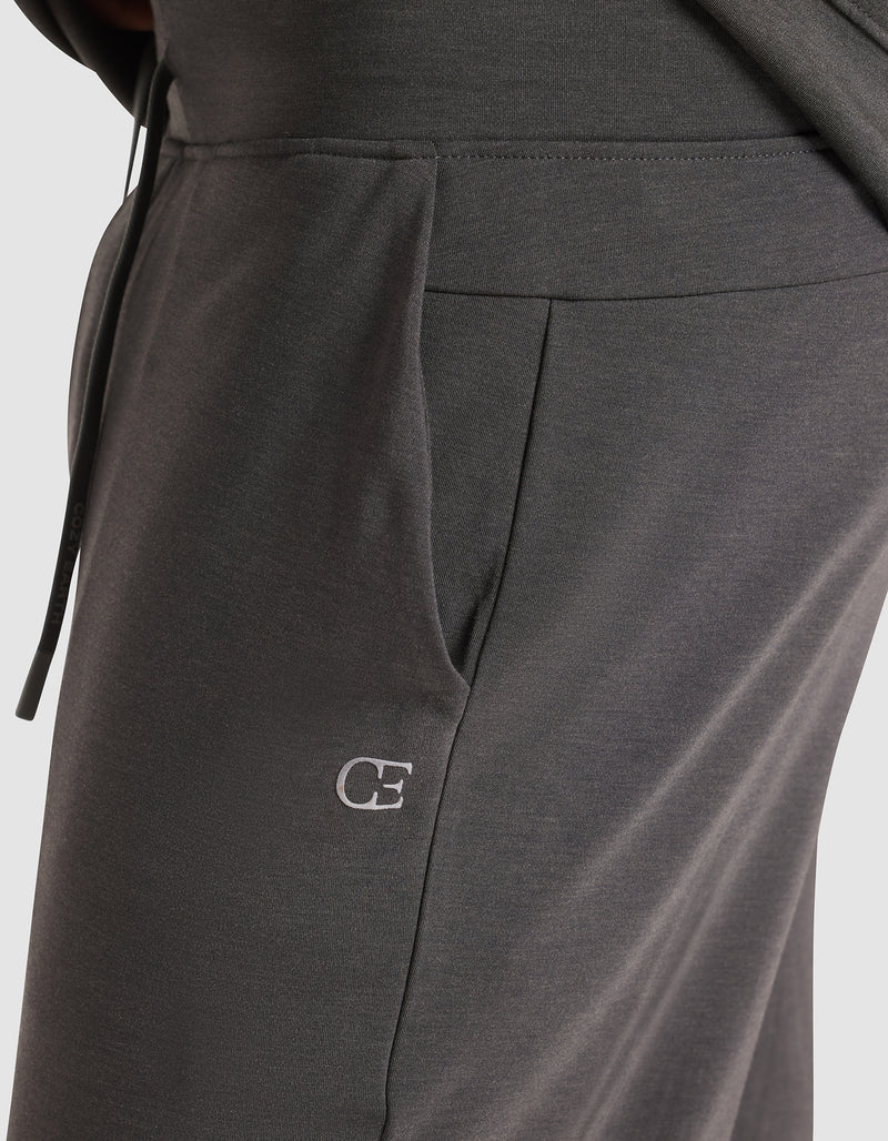 Close-up of a person wearing Cozy Earth's Men's Brushed Bamboo Jogger Pant in dark gray, featuring a visible side pocket and an embroidered white "CE" logo near the pocket.