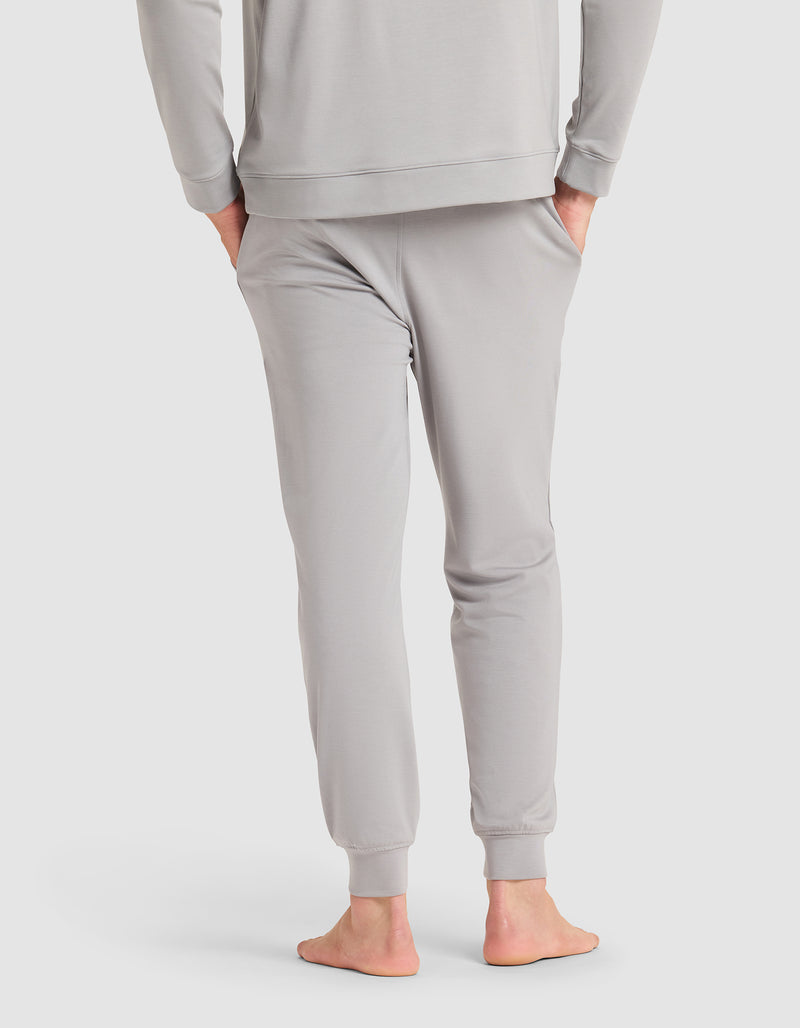 A barefoot man, seen from behind, wears Cozy Earth's Men's Brushed Bamboo Jogger in light gray with a matching long-sleeve top.