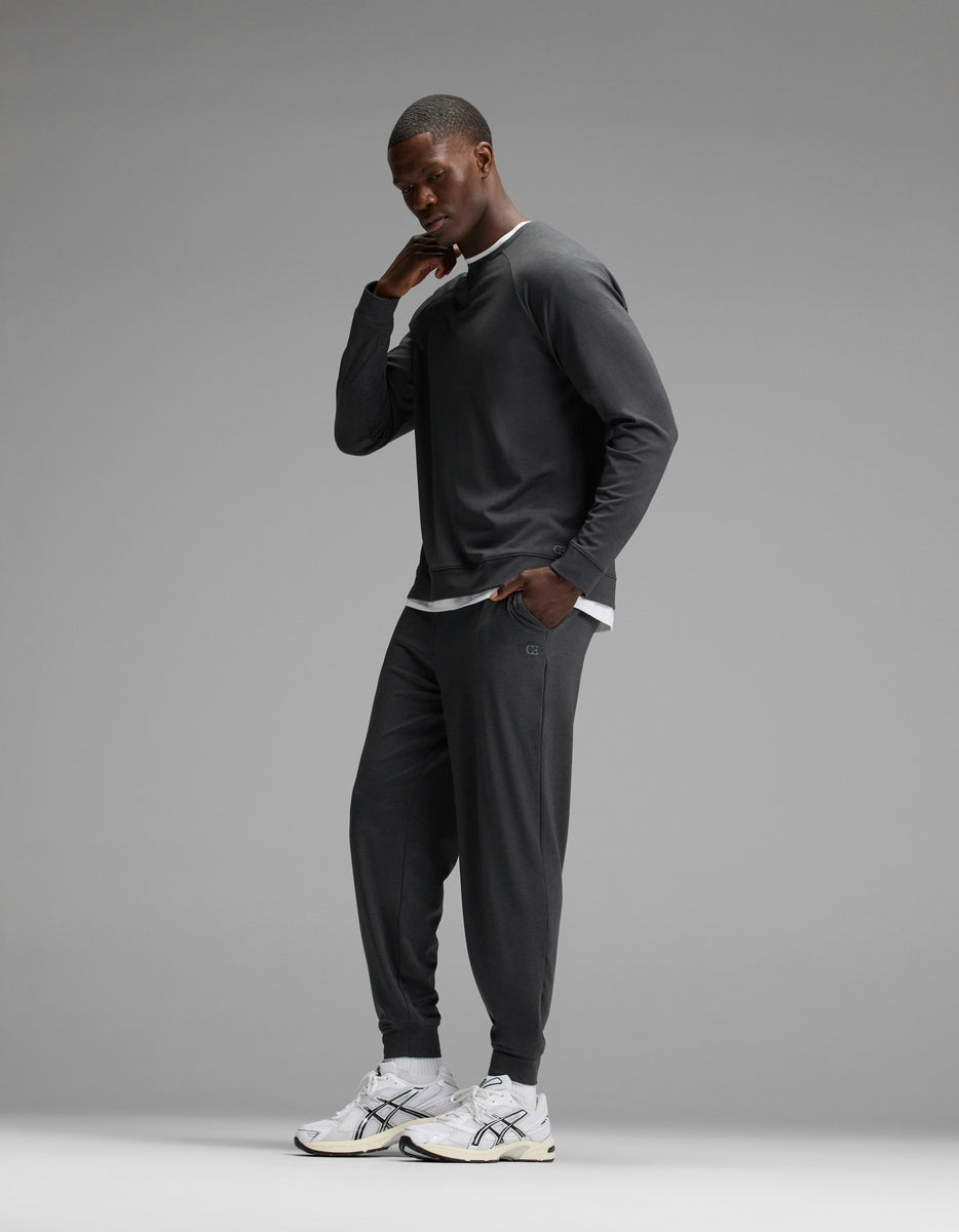 A man stands in a relaxed pose against a plain gray background wearing the Cozy Earth Men’s Brushed Bamboo Jogger Set and white sneakers.