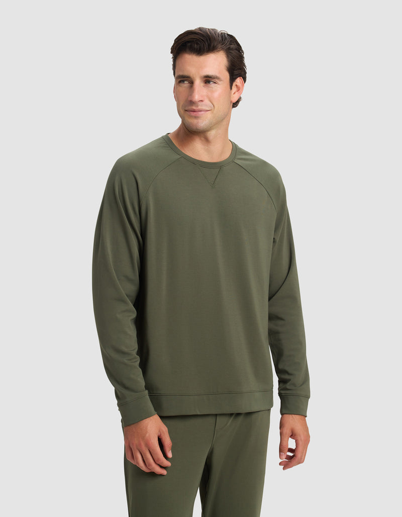 A man wearing the Cozy Earth Men's Brushed Bamboo Pullover Crew in olive green stands against a light gray background, looking slightly to his left with a neutral expression.