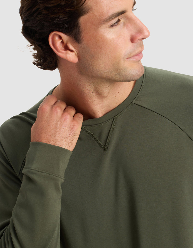 A man models the Cozy Earth Men's Brushed Bamboo Pullover Crew in olive green, touching the collar with his left hand against a plain light background.