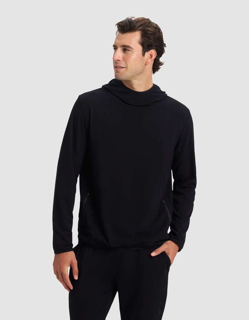 A man wears the Cozy Earth Men's Brushed Bamboo Recovery Hoodie and black pants, standing with one hand in his pocket and looking left against a plain light gray background.
