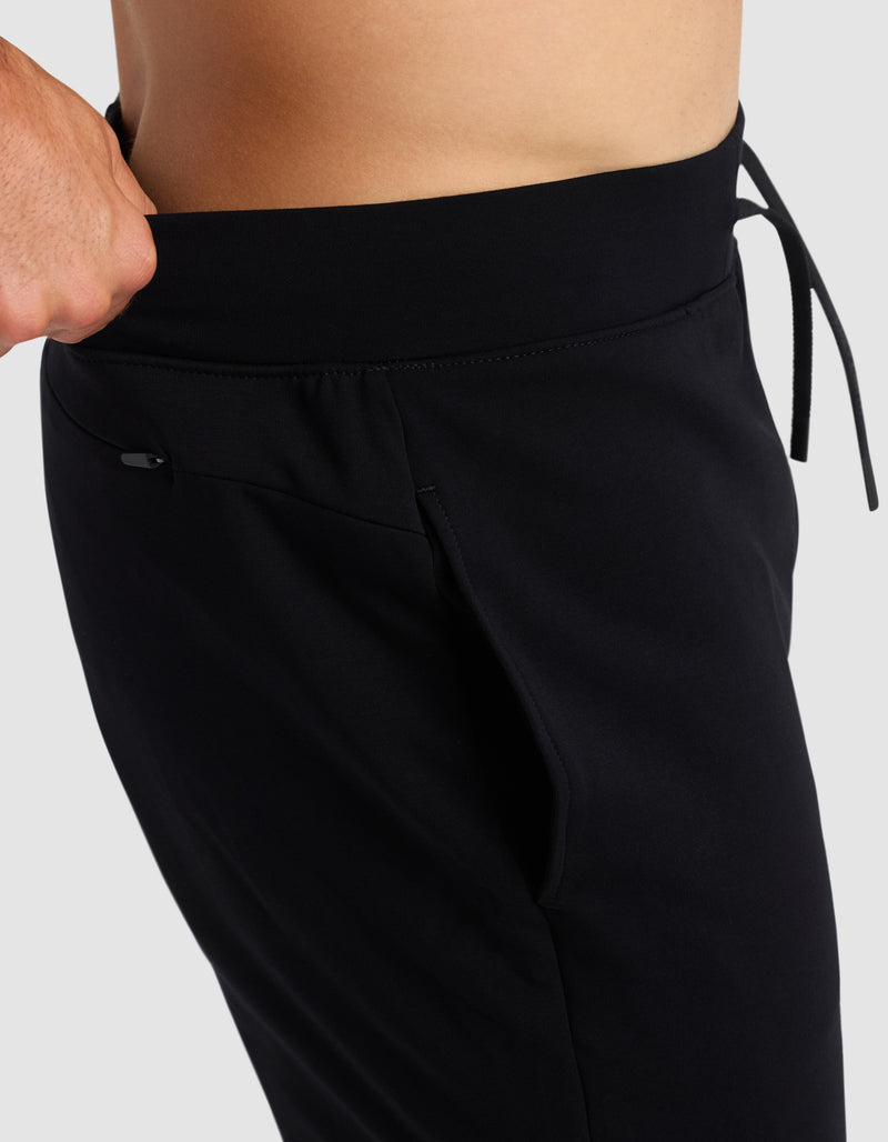 A person adjusts the waistband of Cozy Earth's Men's Brushed Bamboo Recovery Jogger, shown from the side and waist down, featuring a visible drawstring and hand holding the waistband.
