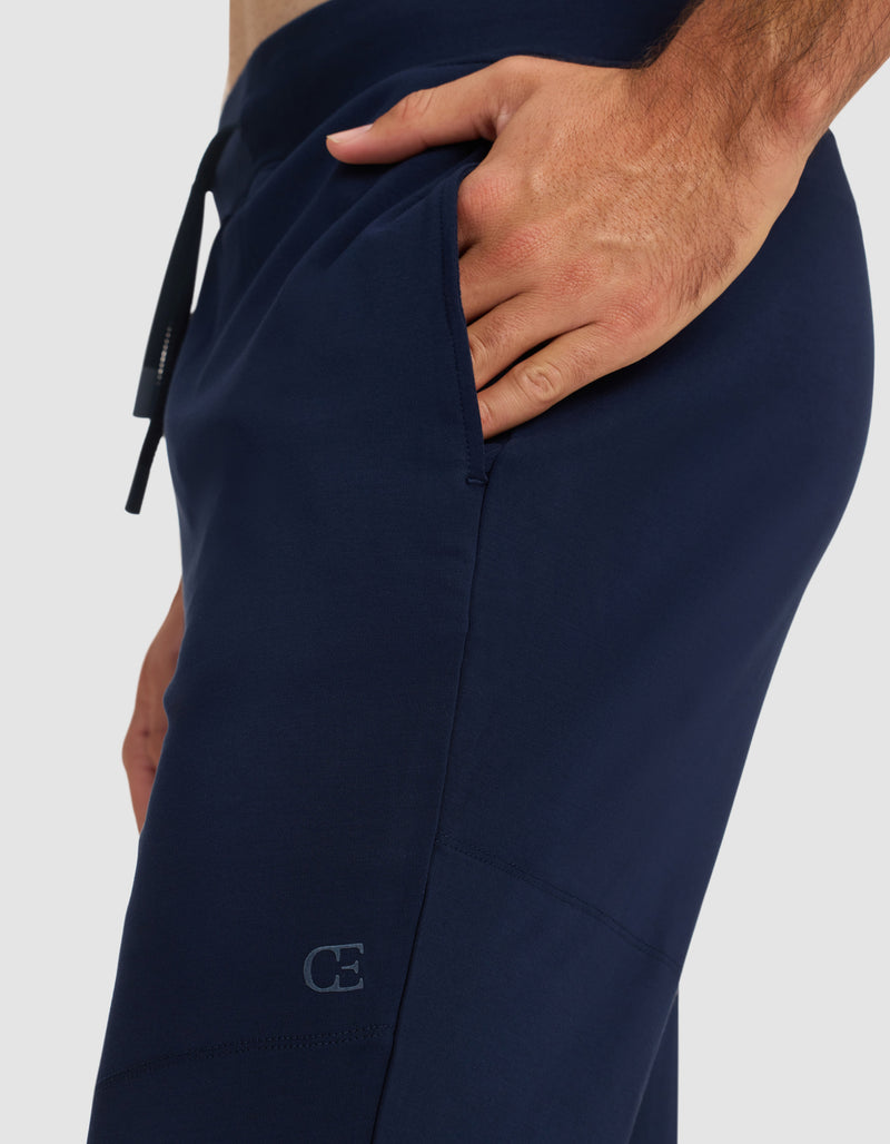 A person wearing Cozy Earth Men's Brushed Bamboo Recovery Jogger in navy blue, with one hand in the pocket, highlights the side detail and a small "CE" logo near the pocket.