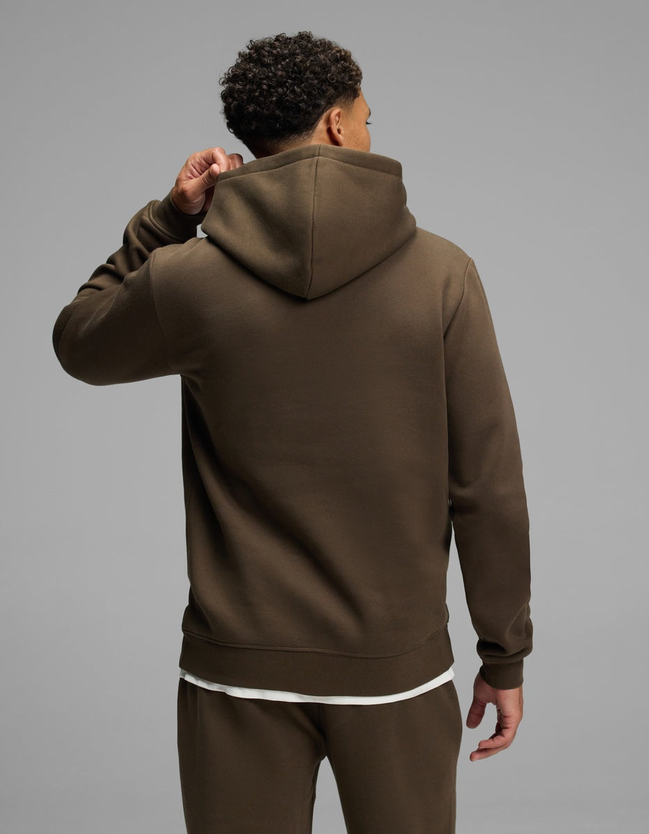 A person seen from the back wearing a dark olive green Men’s Cityscape Hoodie by Cozy Earth.