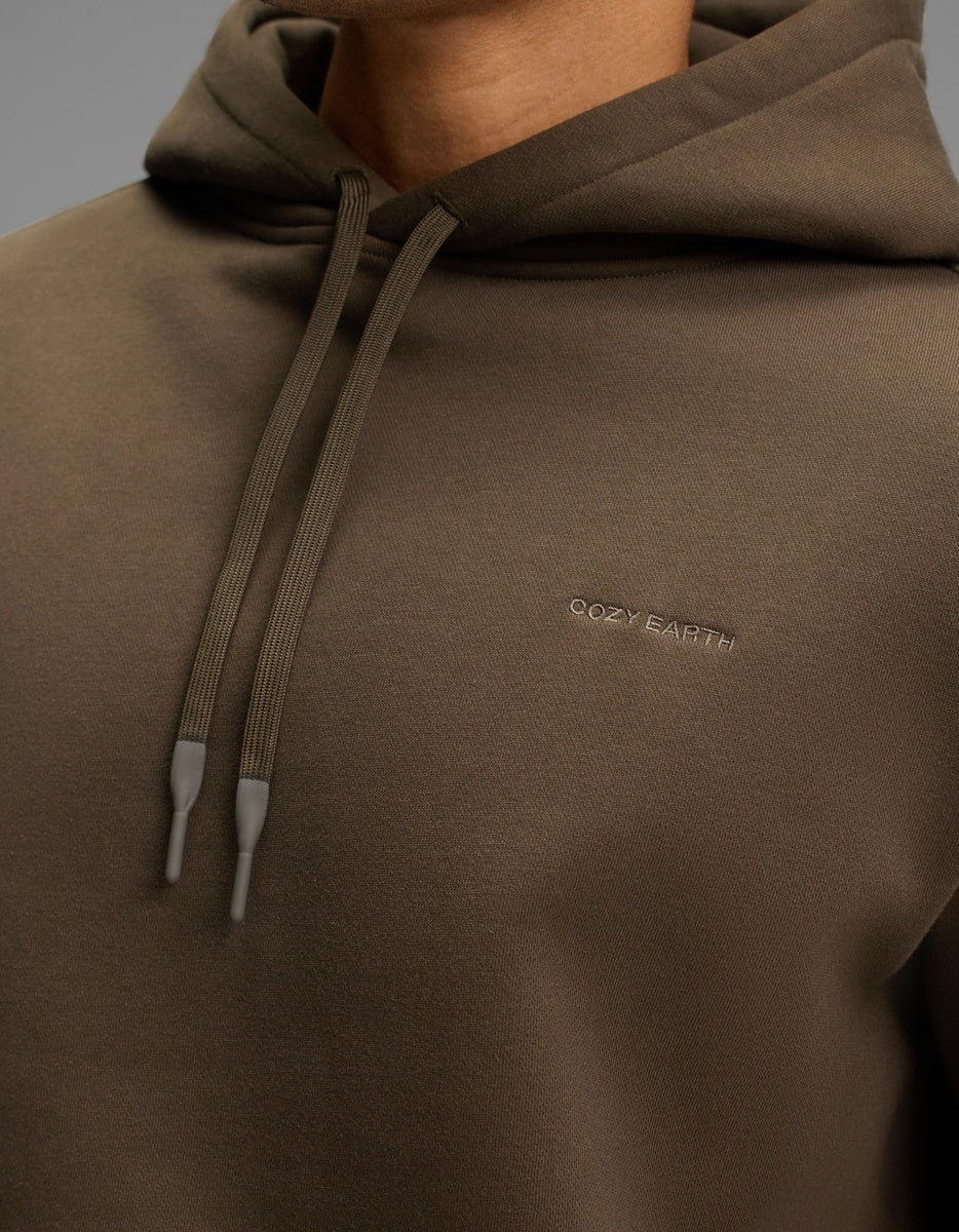 Close-up of a brown Cozy Earth Men’s Cityscape Hoodie with matching drawstrings and the brand name embroidered on the chest.