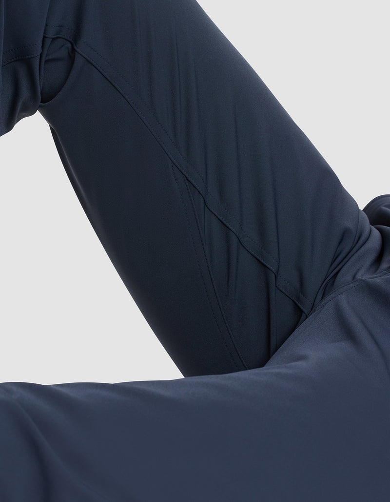 Close-up of a person wearing Cozy Earth Men's Everywhere Pant in dark navy blue, with a bent knee and leg partially visible against a light gray background.