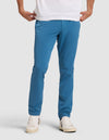 A person models Cozy Earth's Men's Everywhere Pant in bright blue with hands in pockets, paired with a white t-shirt and white sneakers, standing against a plain light gray background. The upper body is cropped from the image.  |Color:Wave