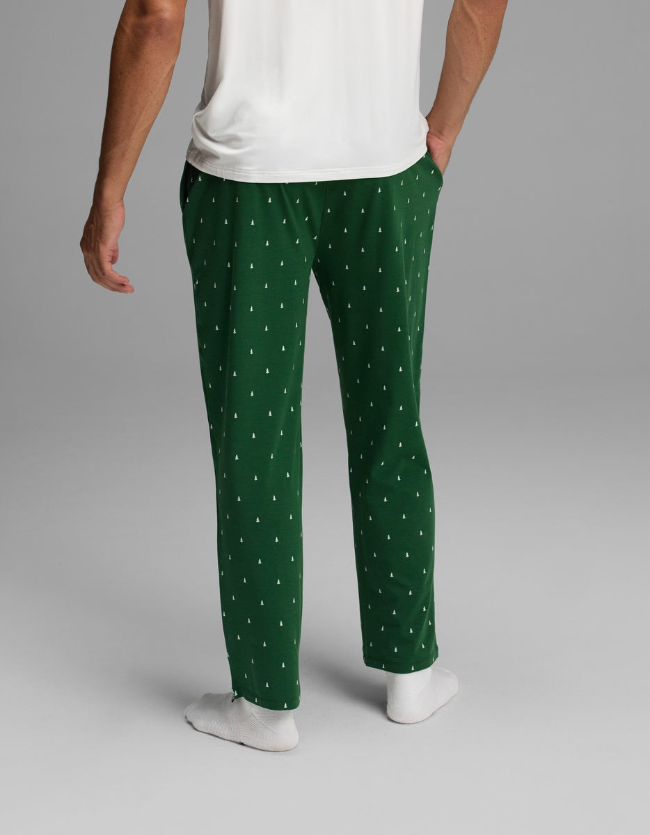 Back view of a person wearing dark green Men’s First Layer Pajama Pant featuring a small white tree pattern.
