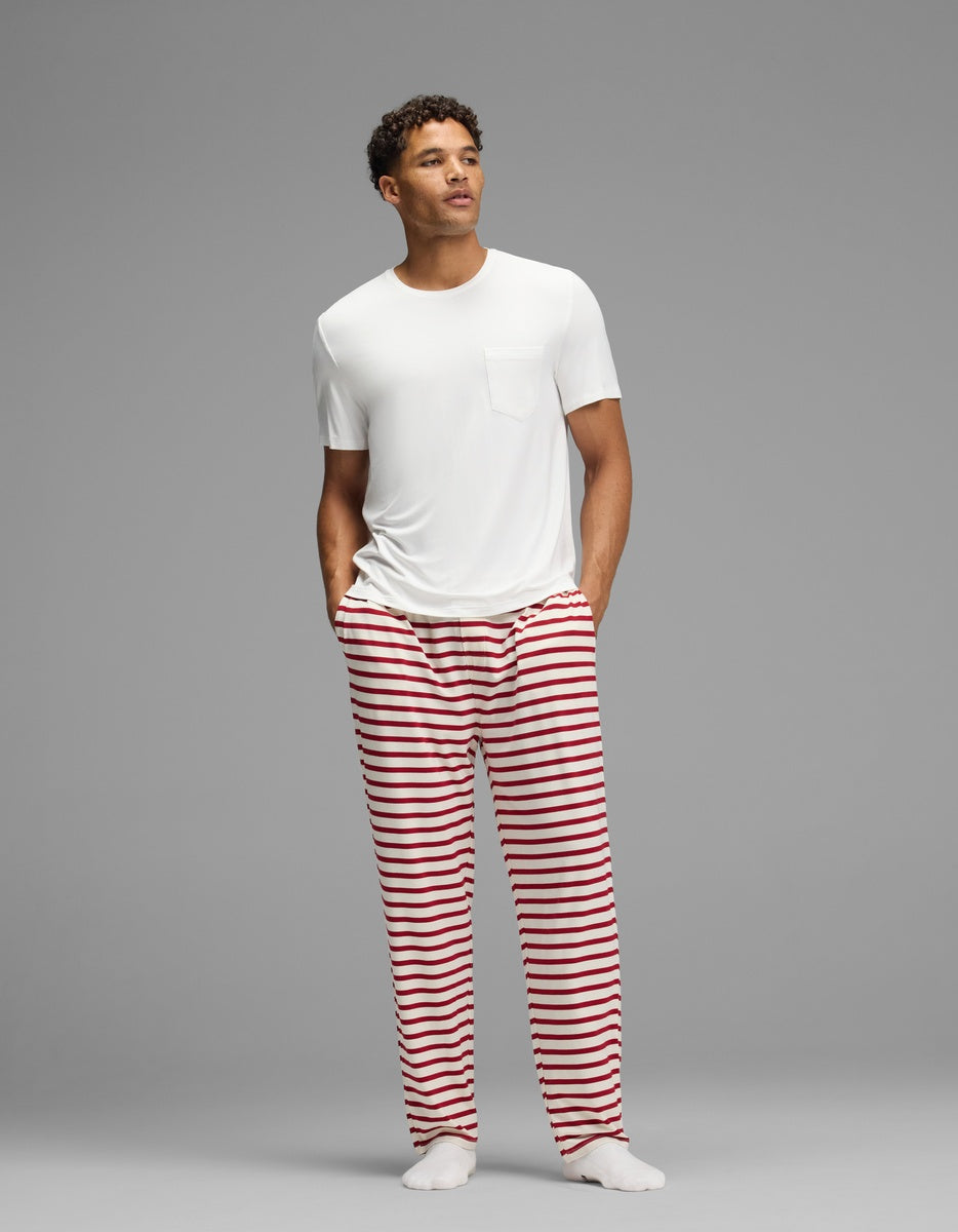 A man wearing a white t-shirt and Cozy Earth Men’s First Layer Pajama Pant featuring horizontal red stripes.