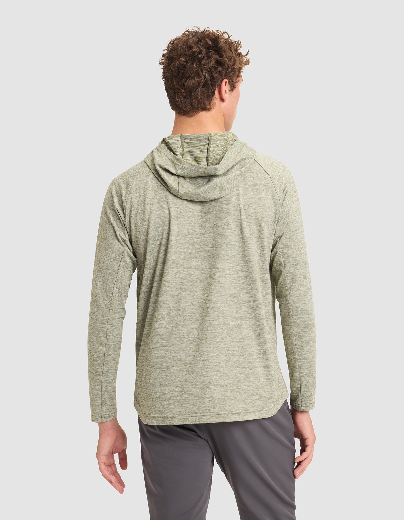 A man with curly hair is seen from behind wearing the Cozy Earth Men's Lightweight Performance Hoodie in light green and gray pants, standing against a plain white background. |Color:Heather Olive