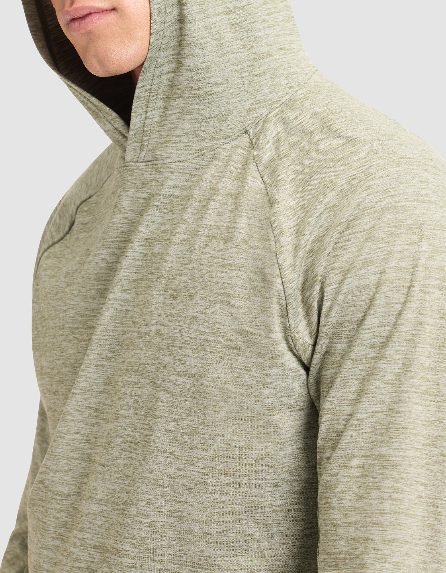 A person models the Cozy Earth Men's Lightweight Performance Hoodie in light green heather, seen from the shoulders up with the hood on and part of their face visible as they turn slightly to the side. |Color:Heather Olive