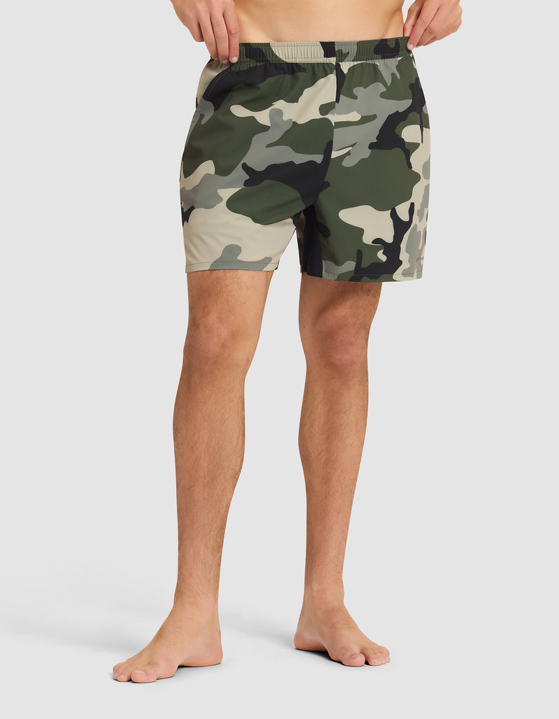 A person stands barefoot in Cozy Earth Men's Day & Night Shorts 5" against a plain light background, showing only the lower torso and legs.