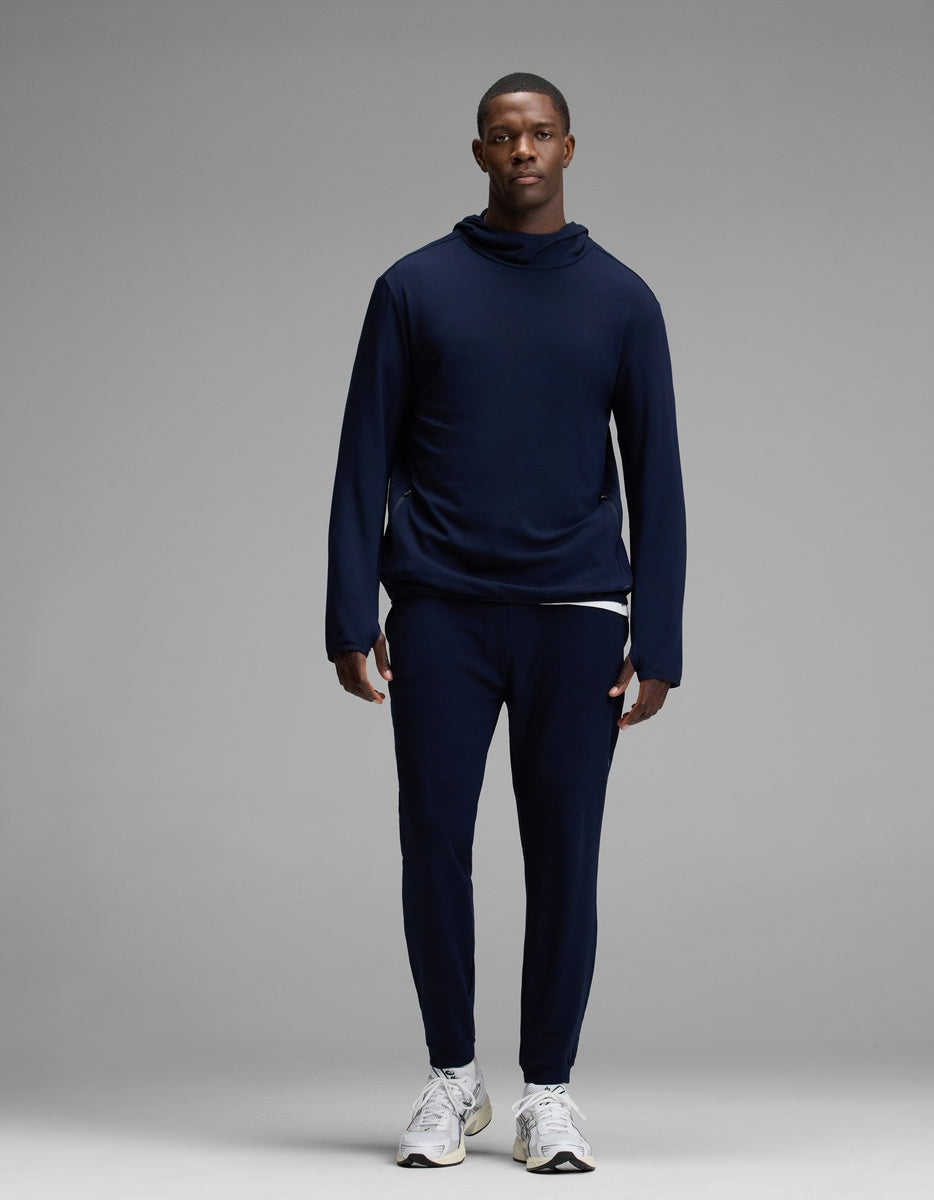 A man stands facing forward, wearing the Cozy Earth Men’s Recovery Jogger set in navy blue with white sneakers, against a plain gray background.|Color:Navy