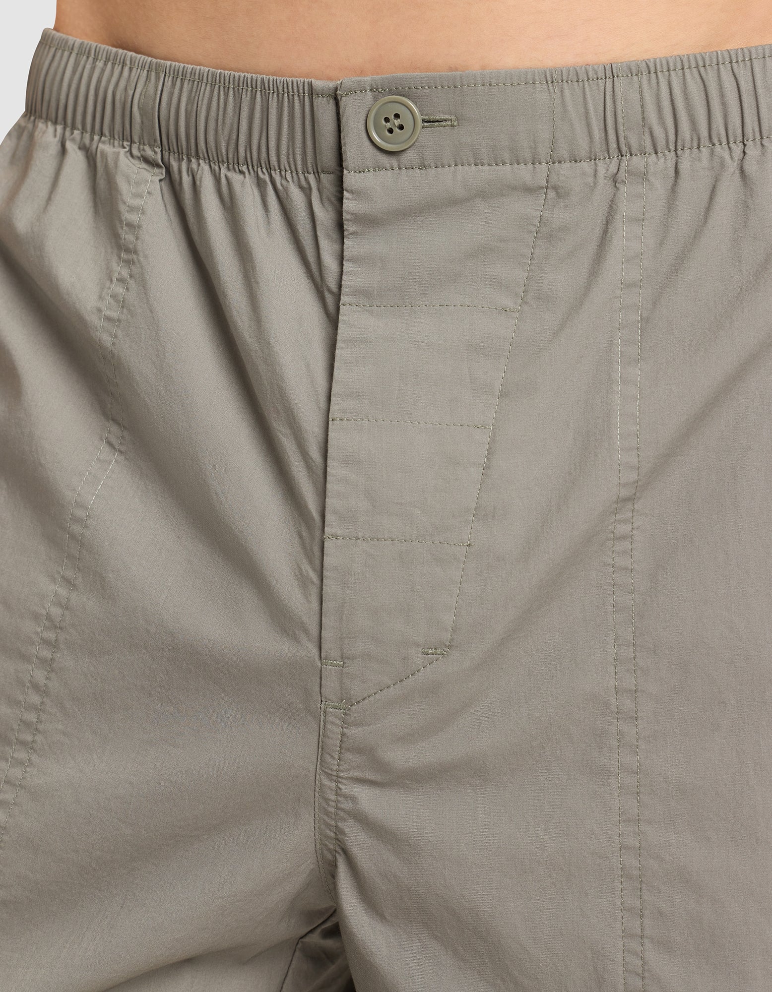 Close-up of a person wearing Cozy Earth Men's Sleep Pant in light gray, featuring an elastic waist, button closure, and visible stitching on lightweight, subtly textured fabric. |Color:Cypress