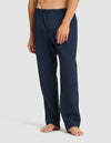 A person is wearing Cozy Earth Men's Sleep Pant in navy blue with an elastic waistband and button, standing barefoot against a plain light background. The upper body is not visible. |Color:Eclipse