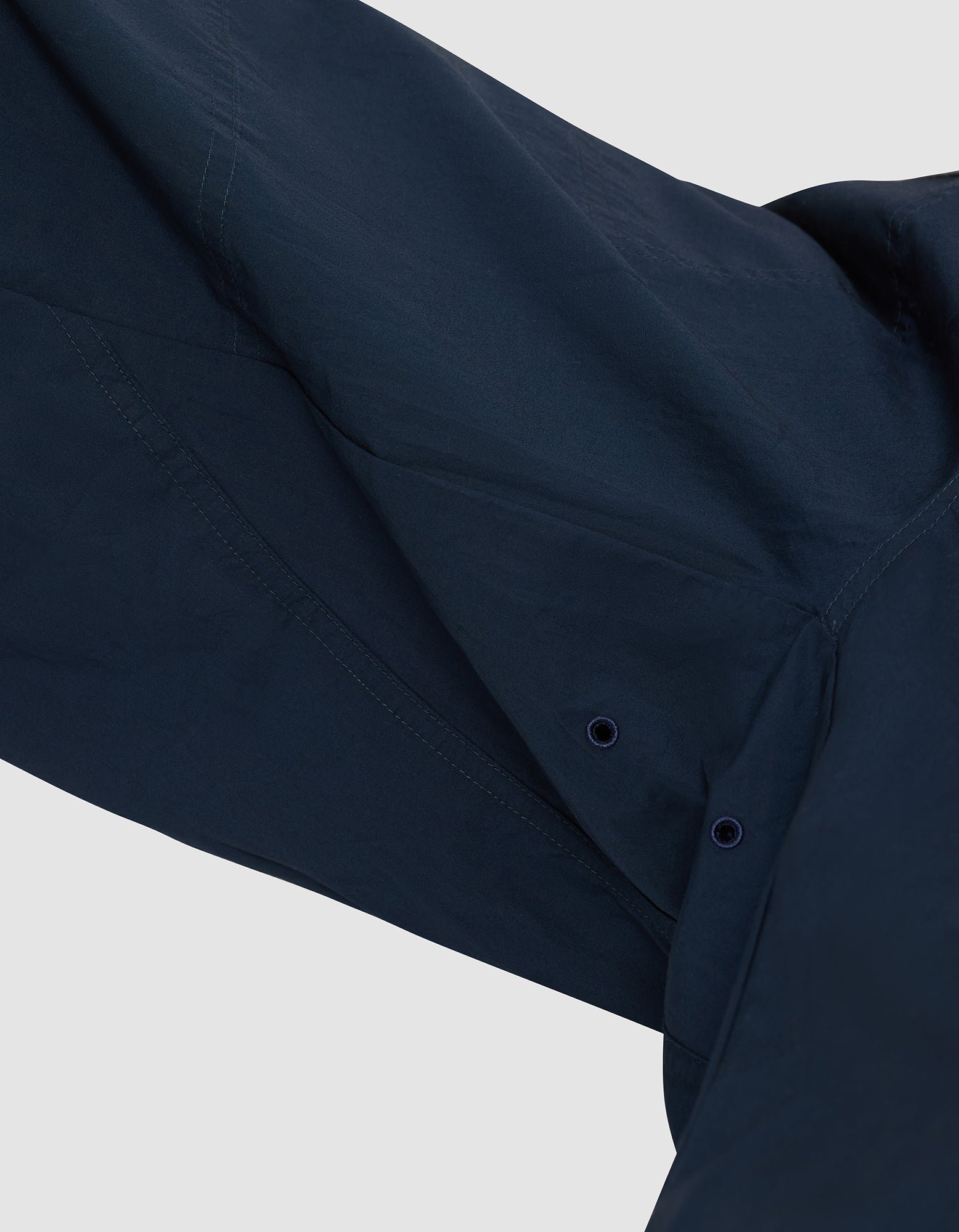 Close-up of the underarm area of the Cozy Earth Men's Sleep Pant in dark blue, showing two small ventilation eyelets and visible stitching that highlight the fabric and construction details. 