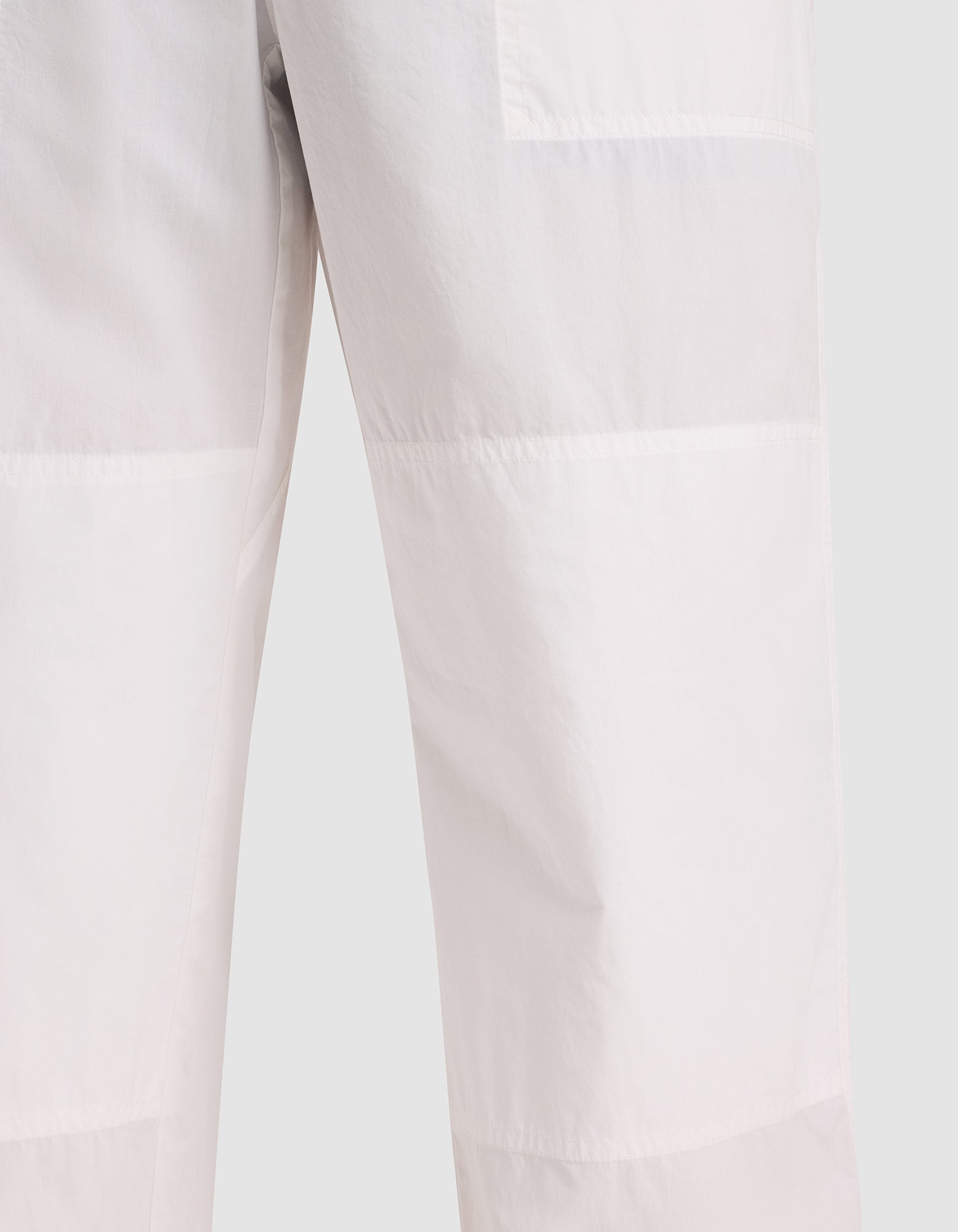 Close-up of Cozy Earth Men's Sleep Pant in a light color, featuring visible stitching and panel detailing, shown against a plain background. 