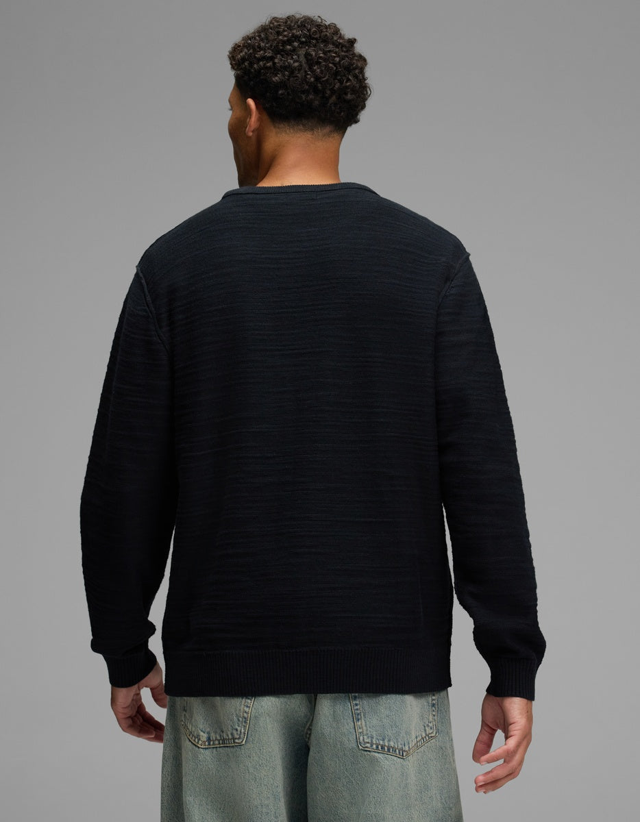 A man from behind wearing a black, ribbed-texture Men’s Tate Crewneck sweater.