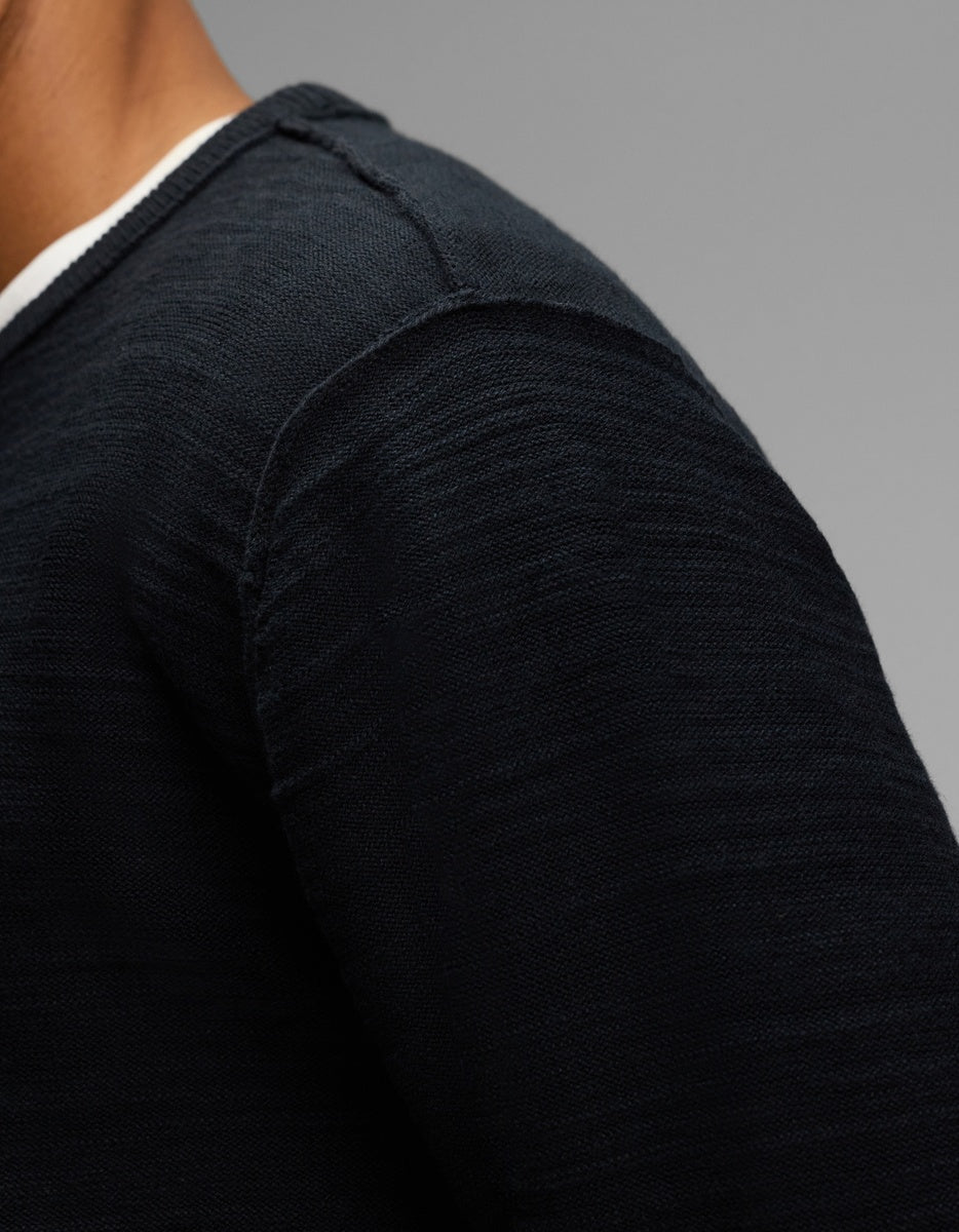 Close-up of a person wearing a dark blue Cozy Earth Men’s Tate Crewneck over a white shirt.