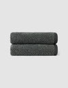 Two dark gray Nantucket Hand Towels by Cozy Earth, neatly rolled and stacked, set against a plain light gray background.|Color:Graphite