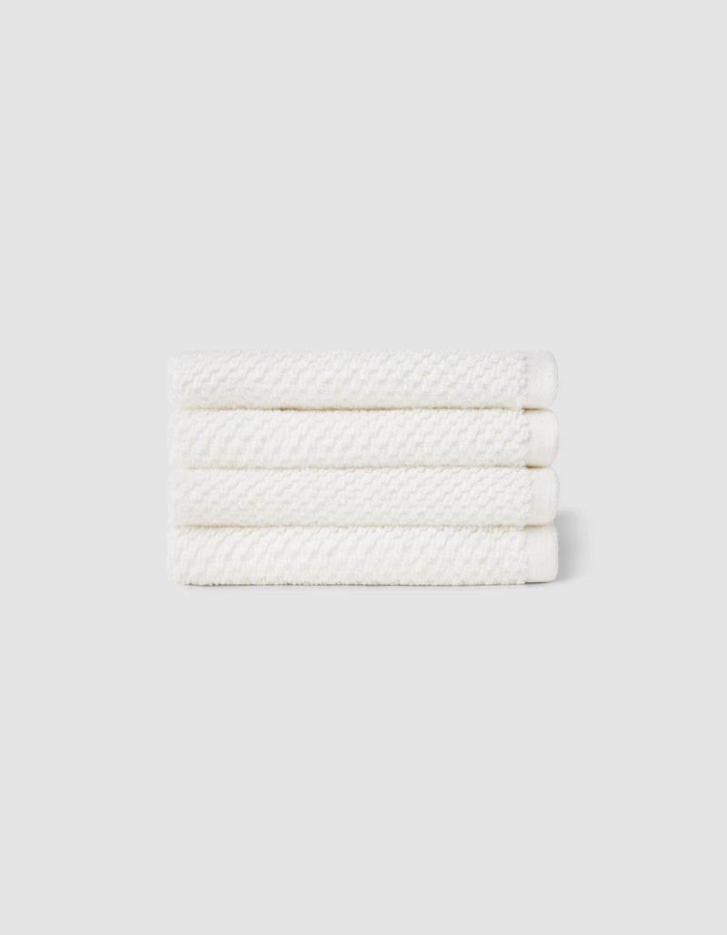 Four neatly folded Nantucket Washcloths by Cozy Earth, stacked horizontally against a plain light gray background.