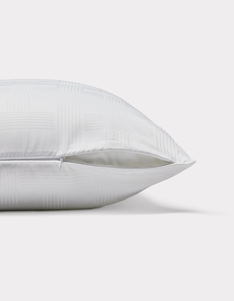 The Cozy Earth Pillow Protector is displayed lying on its side, featuring a subtle checkered pattern and a partially open zipper that reveals the inner filling. The background is plain white.