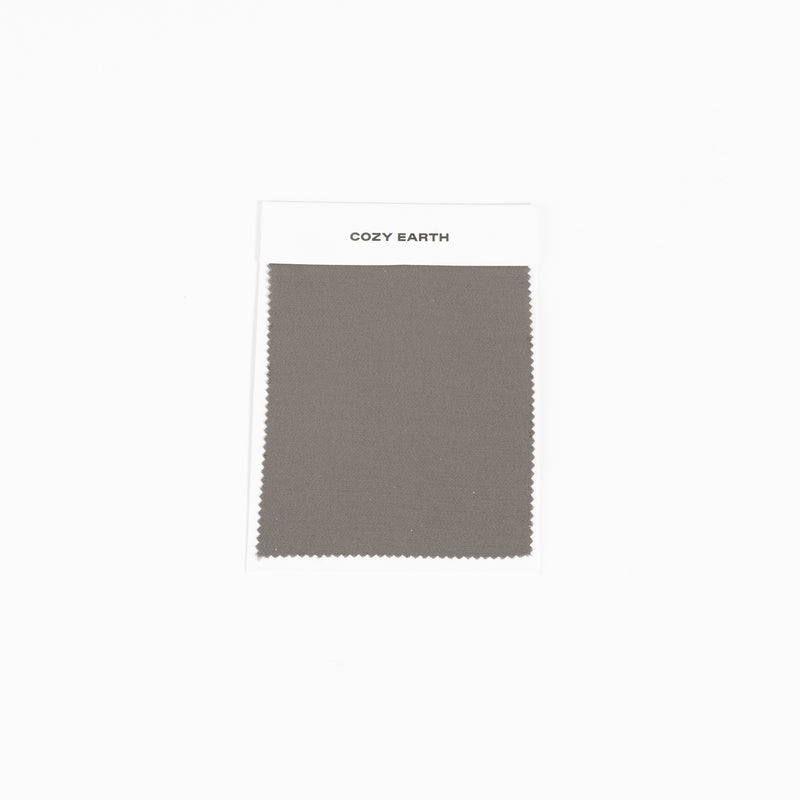 A fabric swatch labeled "Bamboo Sheet Swatch" by Cozy Earth is displayed against a plain white background. The fabric is a solid gray color.