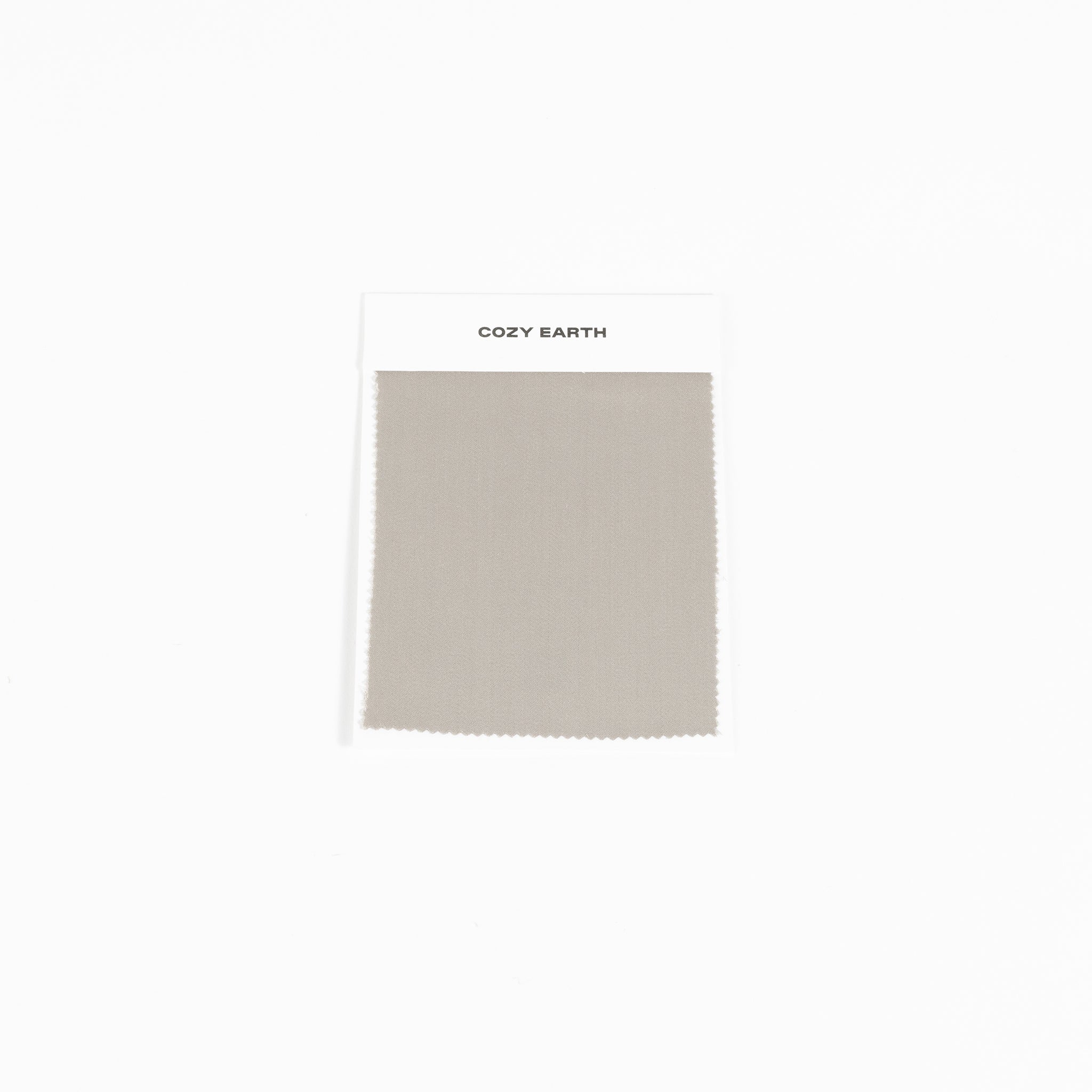 A swatch from the Bamboo Sheet collection by Cozy Earth is shown against a white background. It features a white label at the top with the brand name, "COZY EARTH. |Color:Dove Grey