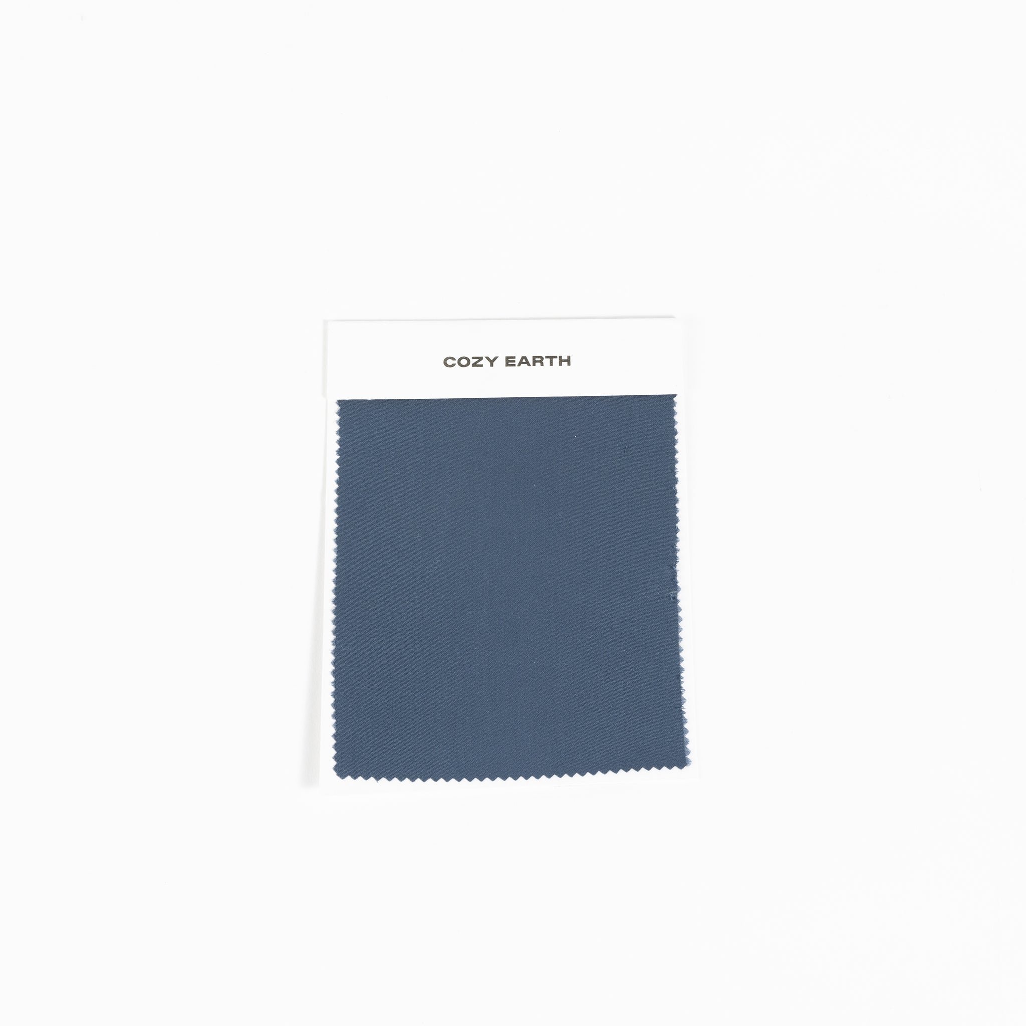 A fabric swatch from the Bamboo Sheet collection by Cozy Earth features a deep blue color, with zigzag-cut edges, set against a plain white background. |Color:Pacific Blue
