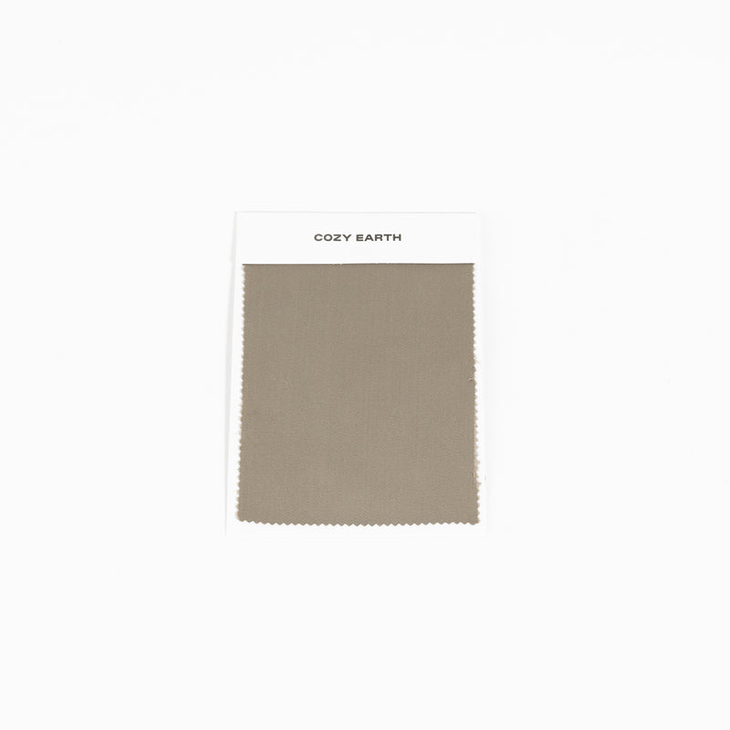 An olive green Bamboo Sheet Swatch with a fine texture and neatly cut edges is displayed on a white card labeled "Cozy Earth" against a plain white background.
