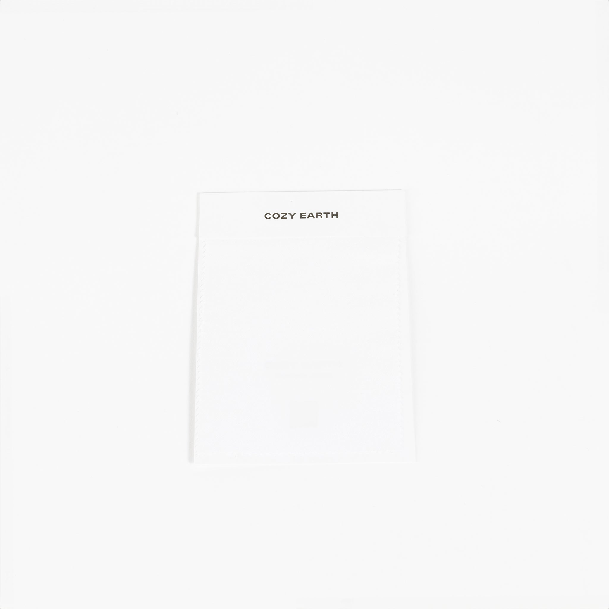 A white fabric label prominently displays the brand name "Cozy Earth" at the top, set against a plain white background to highlight its minimalist design. |Color:White