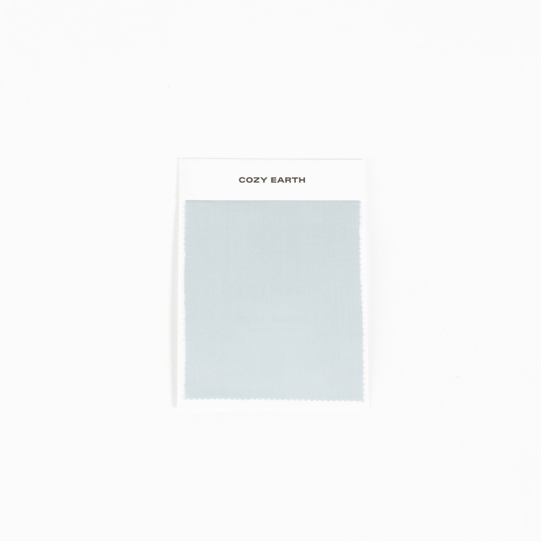 A sample of the bamboo sheet fabric in light gray is displayed against a white background, mounted on a card labeled with "Cozy Earth" at the top. |Color:Shore