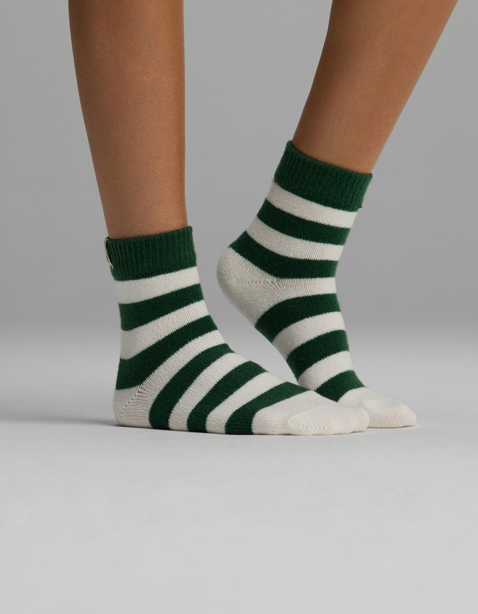 A person wearing green and white striped Women’s Plush Lounge Quarter Sock plush socks.
