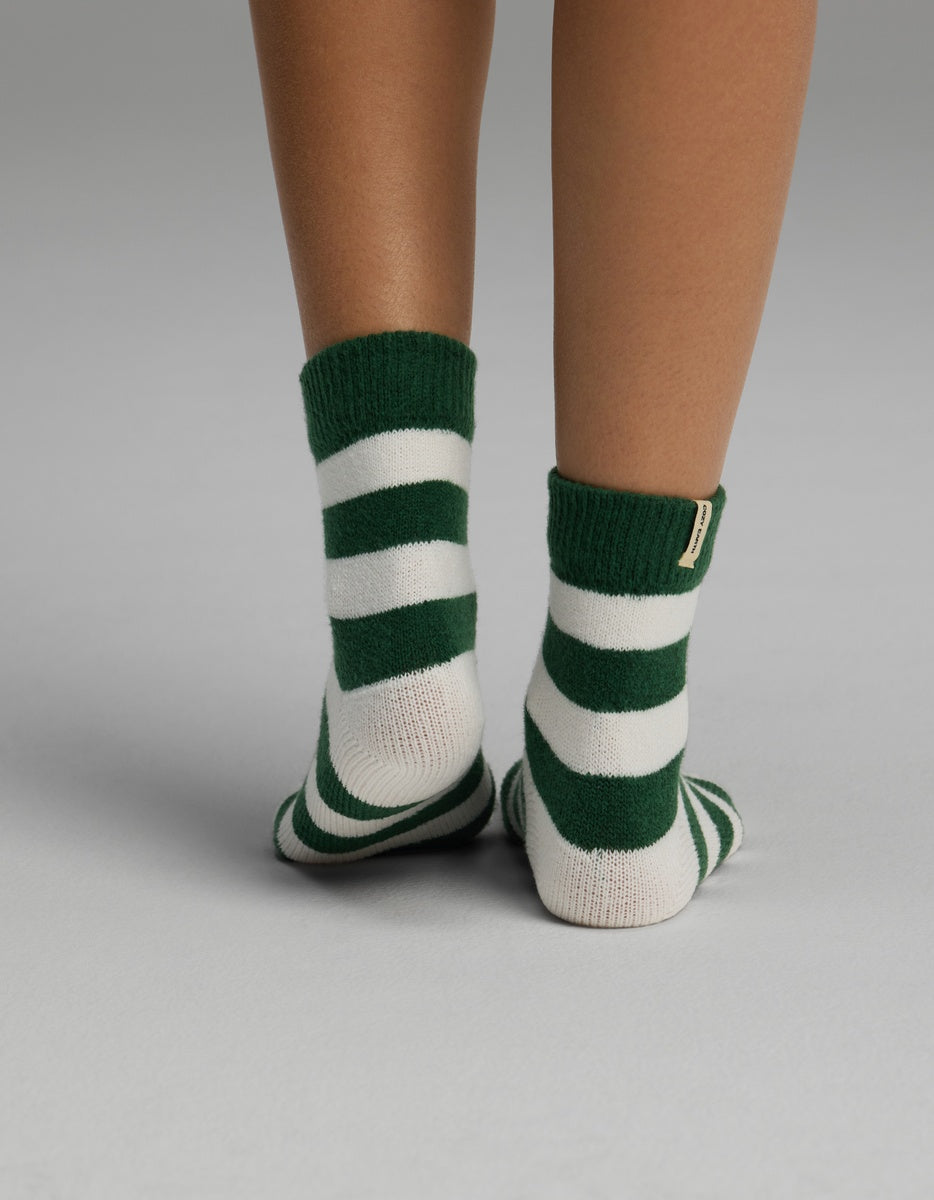 A pair of ankles wearing green and white striped Women’s Plush Lounge Quarter Sock.