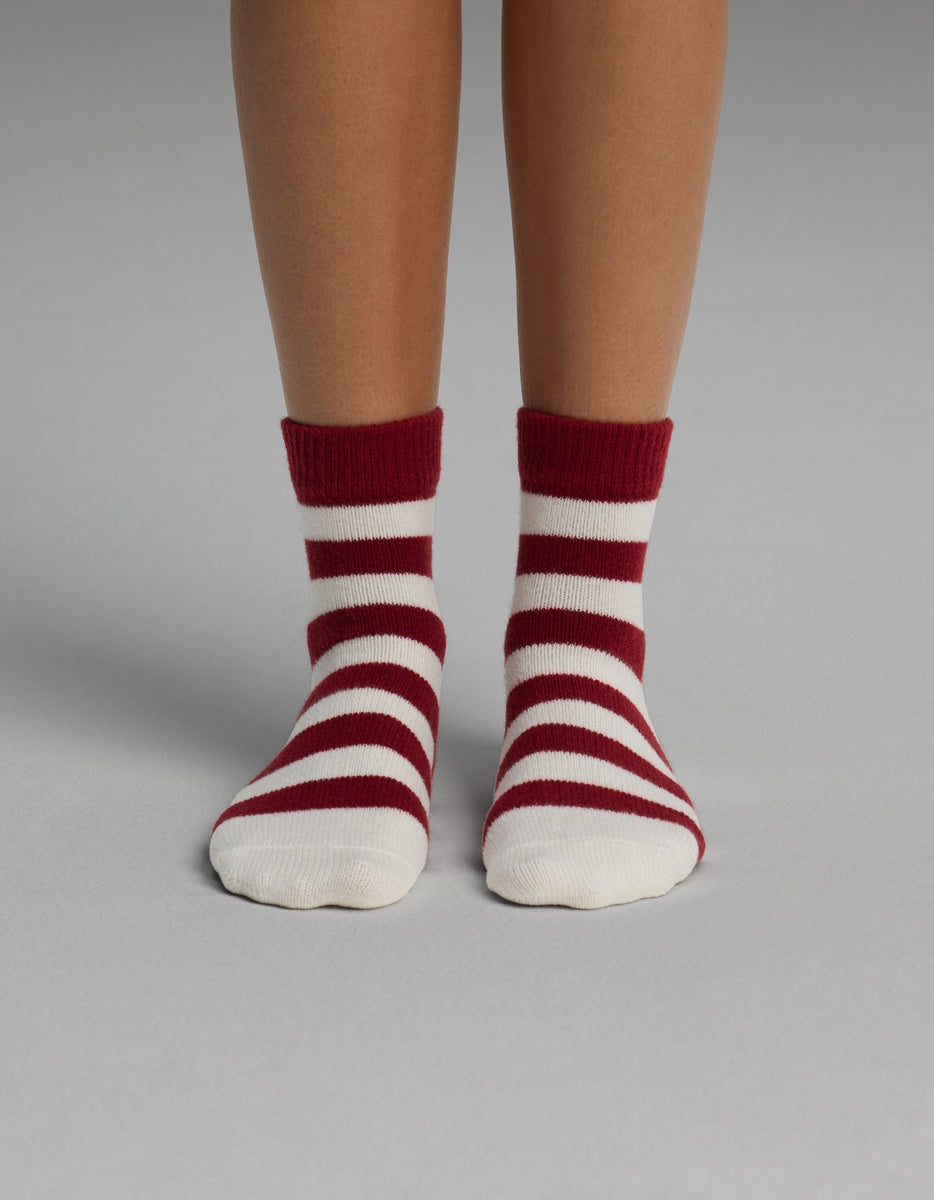 A person wearing Cozy Earth Women’s Plush Lounge Quarter Socks featuring horizontal red and white stripes.