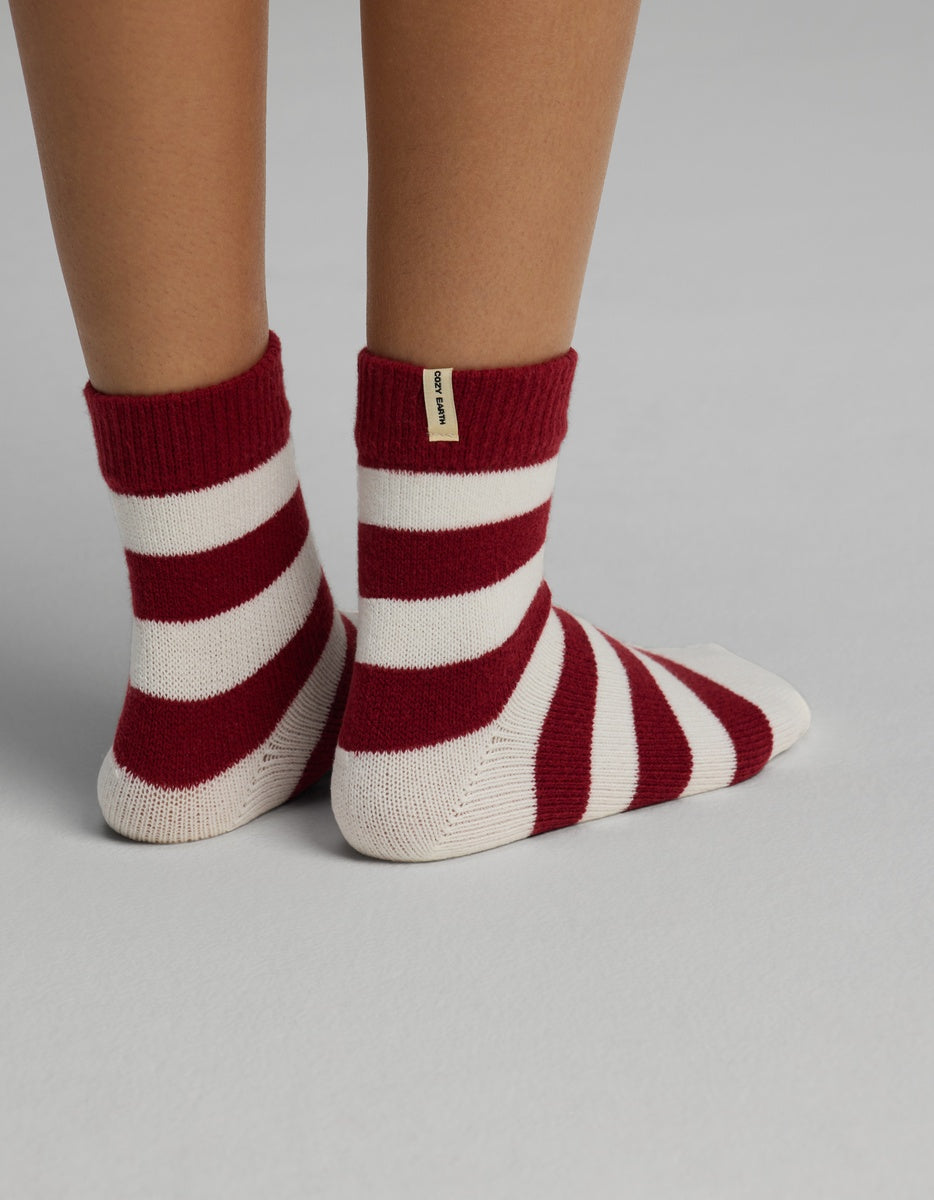 A person wearing Cozy Earth Women’s Plush Lounge Quarter socks with horizontal red and white stripes.