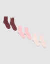 Three pairs of The Plush Modern Crew Sock 3-Pack by Cozy Earth, displayed diagonally on a light background in dark burgundy, pink, and light pink or white shades.|Color:Burgundy/Tulip/Blossom