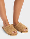 A person wears Cozy Earth’s Puffy Sheep Slides—fuzzy, tan open-toe slippers with thick, textured uppers and flat soles—standing on a white background.|Color:Fawn