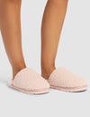A person wears Cozy Earth Puffy Sheep Slippers in light pink, featuring a soft, sherpa-like texture and flat sole, while standing on a light gray surface. Only their lower legs and feet are visible.|Color:Blossom