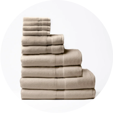Cozy Earth Luxe Bath Sheets, Towels, Hand Towels, and Washcloths in Sand color are stacked on each other.