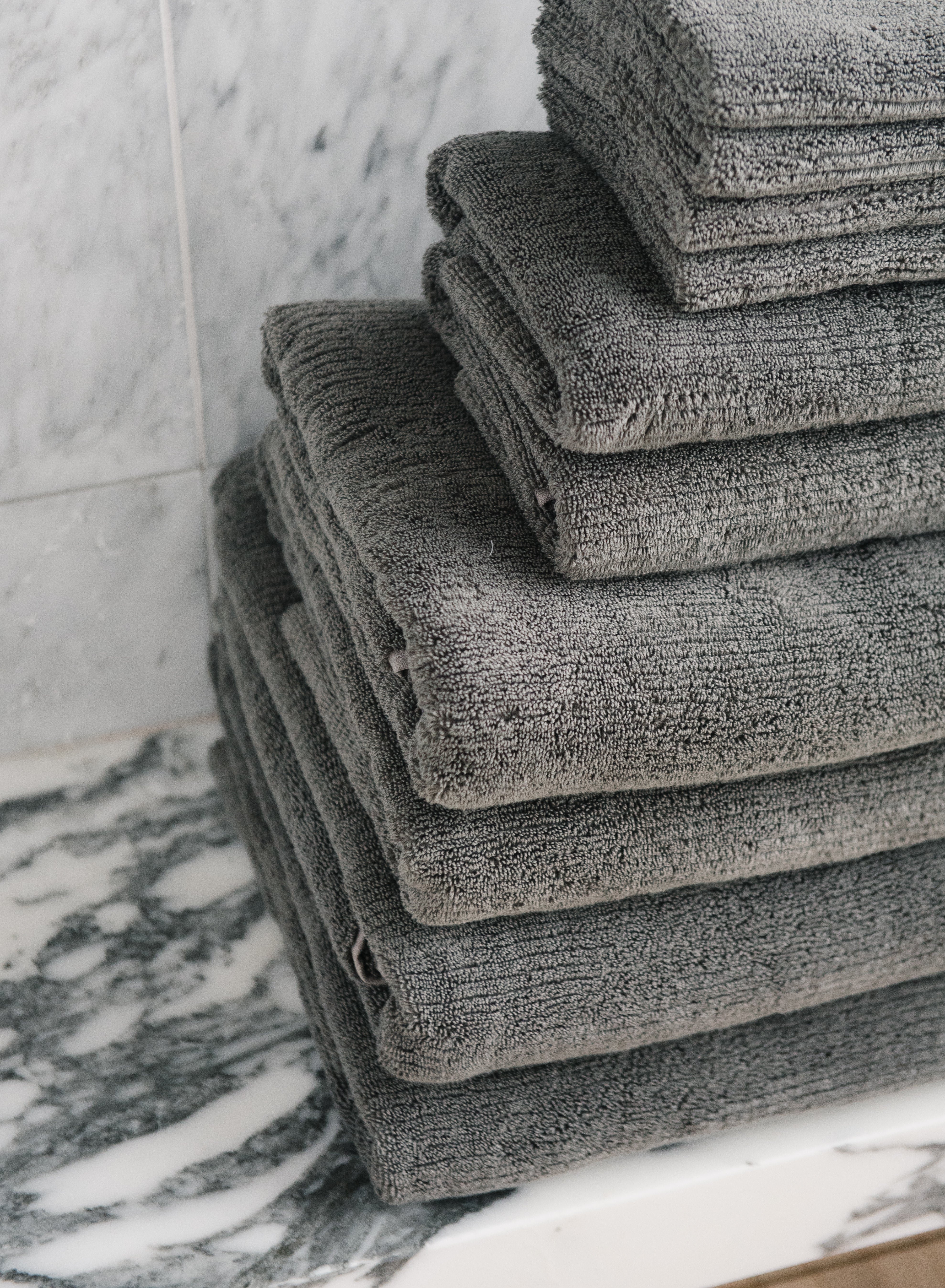Complete Ribbed Terry Bath Bundle in the color Charcoal. Photo of Complete Ribbed Terry Bath Bundle taken in a marble bathroom. The Complete Ribbed Terry Bath Bundle are resting on a marble counter top. 