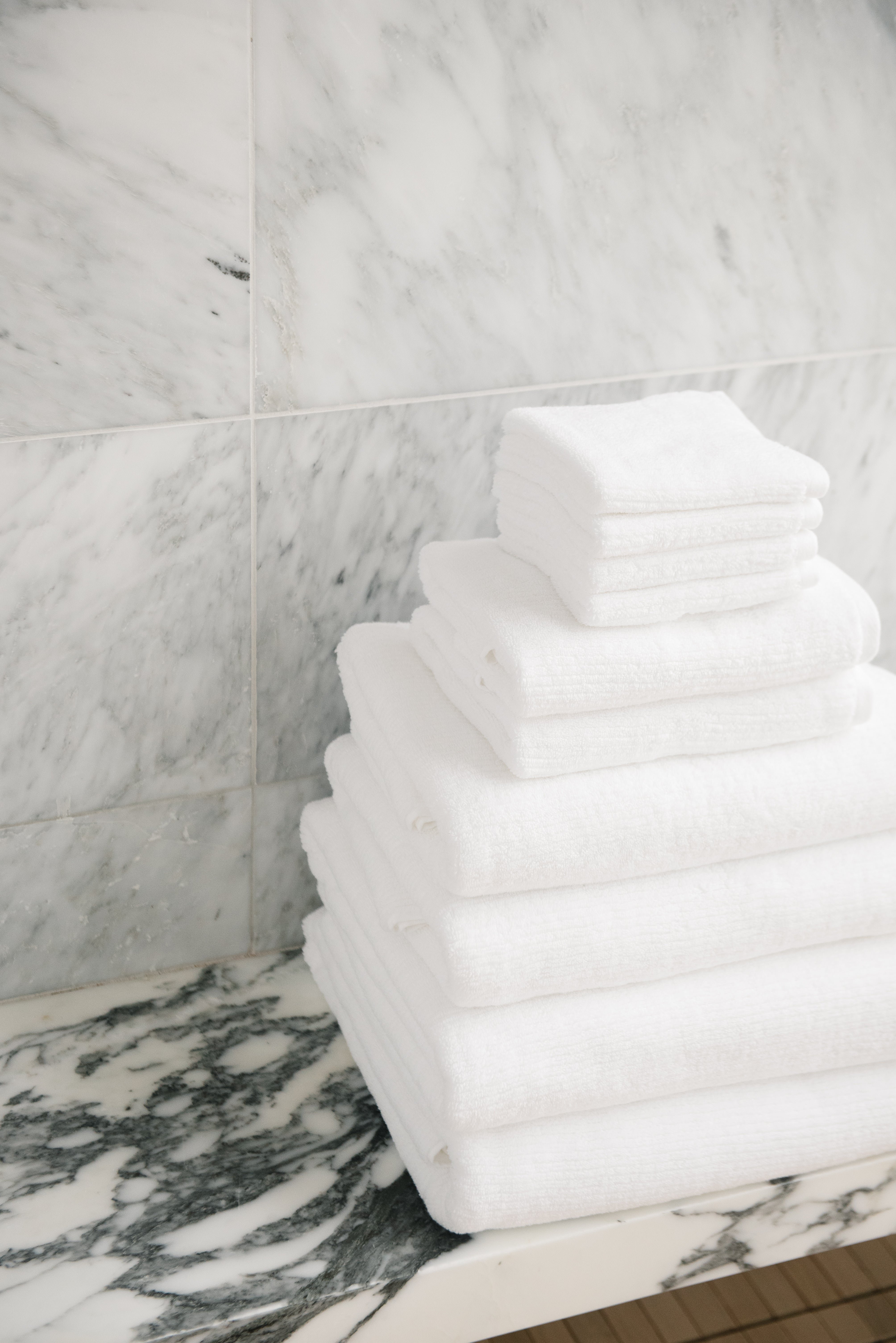 Complete Ribbed Terry Bath Bundle in the color White. Photo of Complete Ribbed Terry Bath Bundle taken in a marble bathroom. The Complete Ribbed Terry Bath Bundle are resting on a marble counter top. 