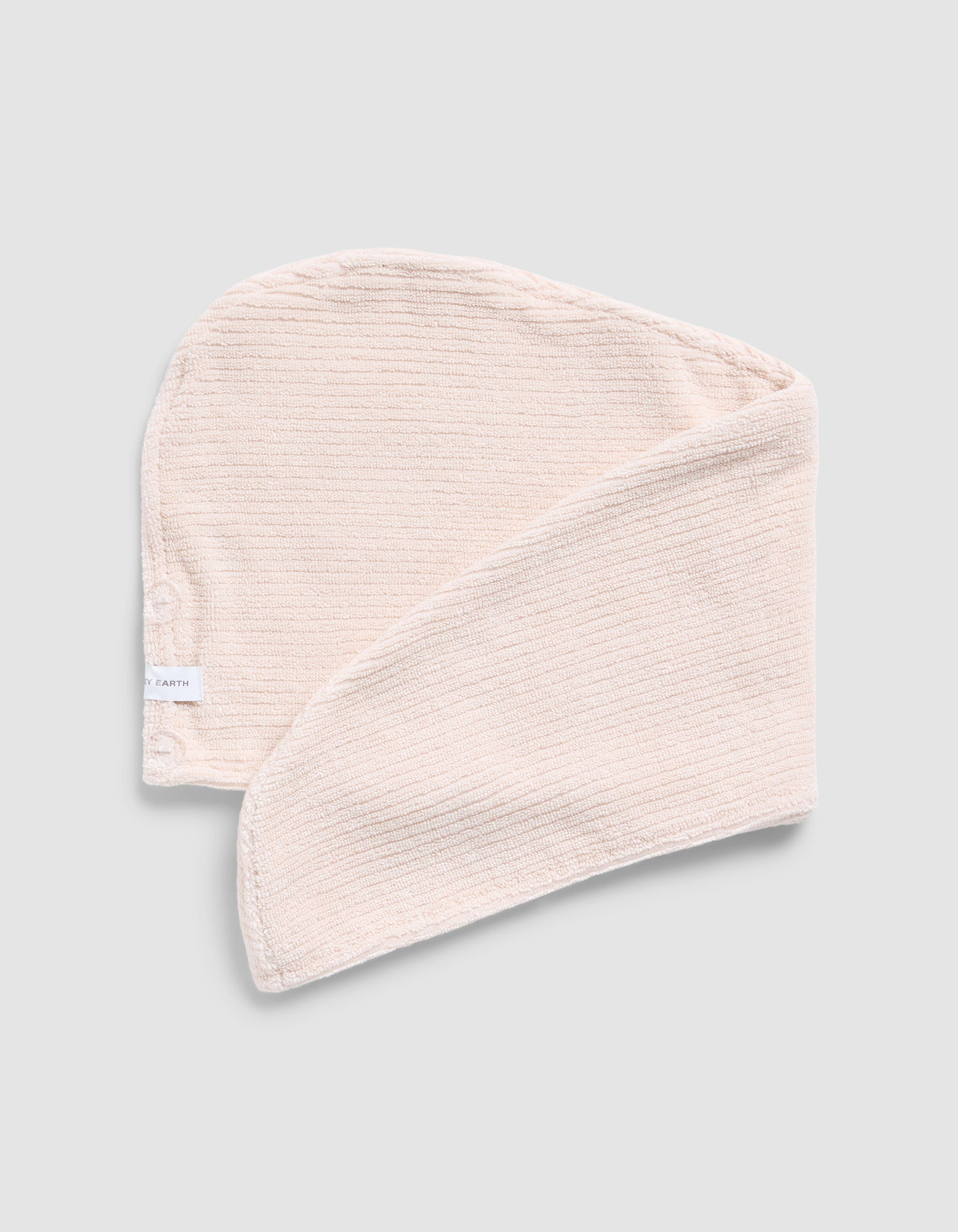 A folded Ribbed Terry Hair towel in Petal on a grey background 